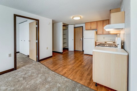 A kitchen area with a white fridge and a wooden floor.