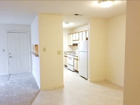 an empty kitchen with white appliances and a white door