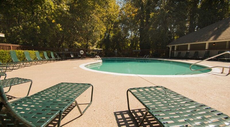 a swimming pool with green chairs around it