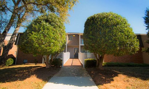 an apartment building with a sidewalk and trees in front of it