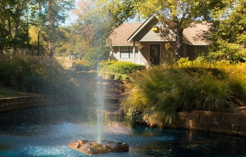a fountain in a pond in front of a house