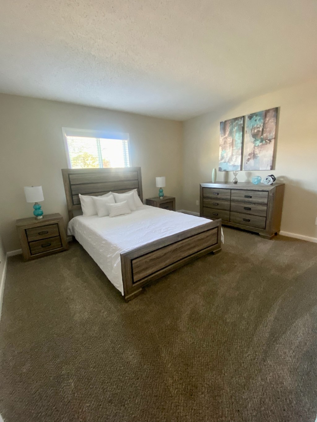 a bedroom with a bed and dressers and a window