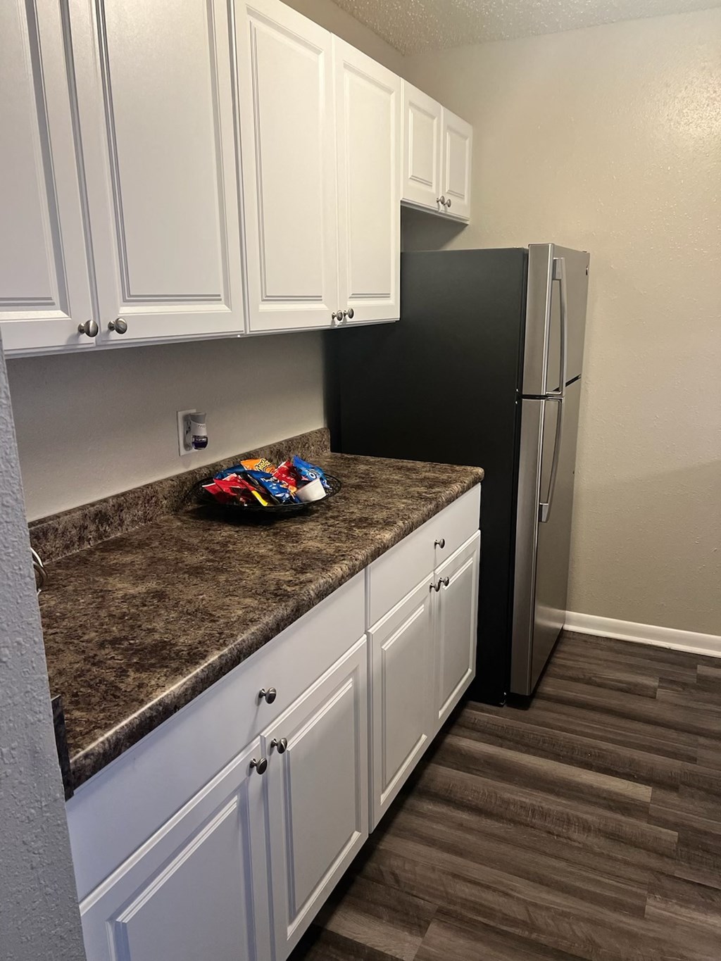 a kitchen with white cabinets and a black refrigerator