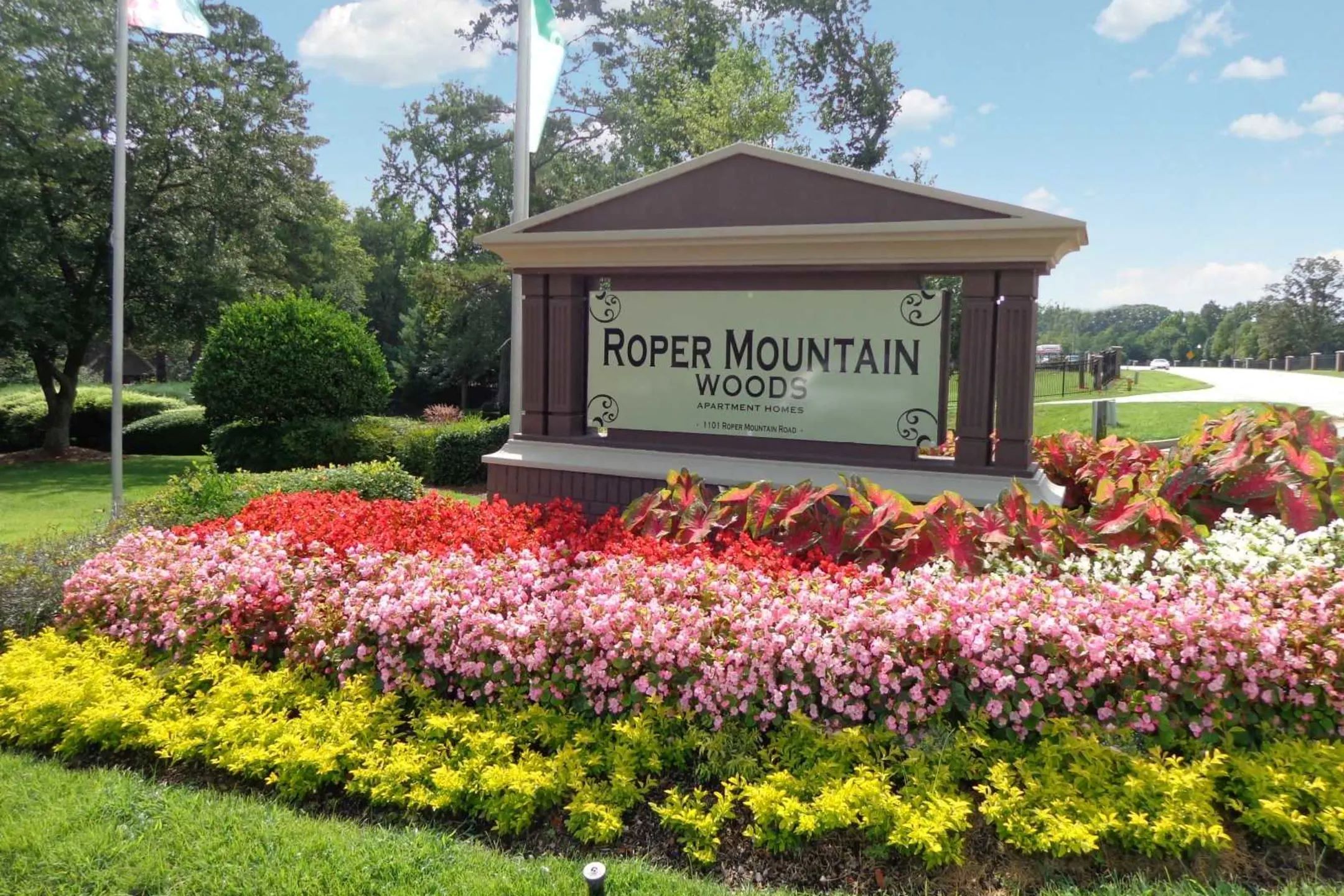 the sign for roper mountain wood in front of a garden of flowers