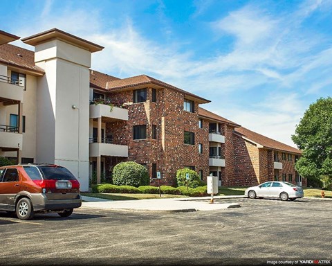 an apartment building with cars parked in a parking lot