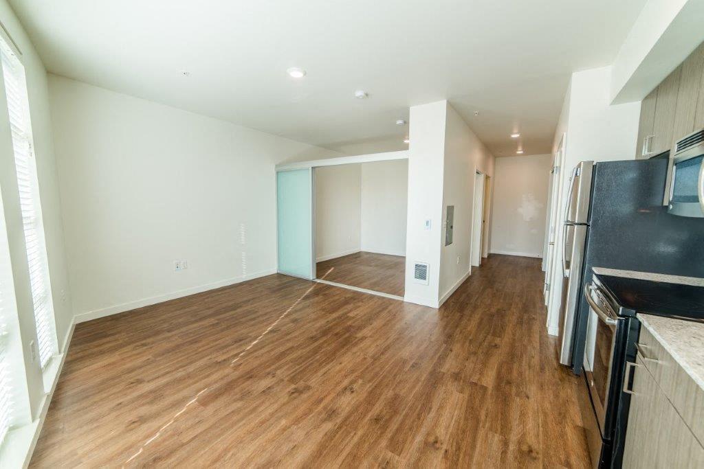 an empty living room and kitchen with a wood floor