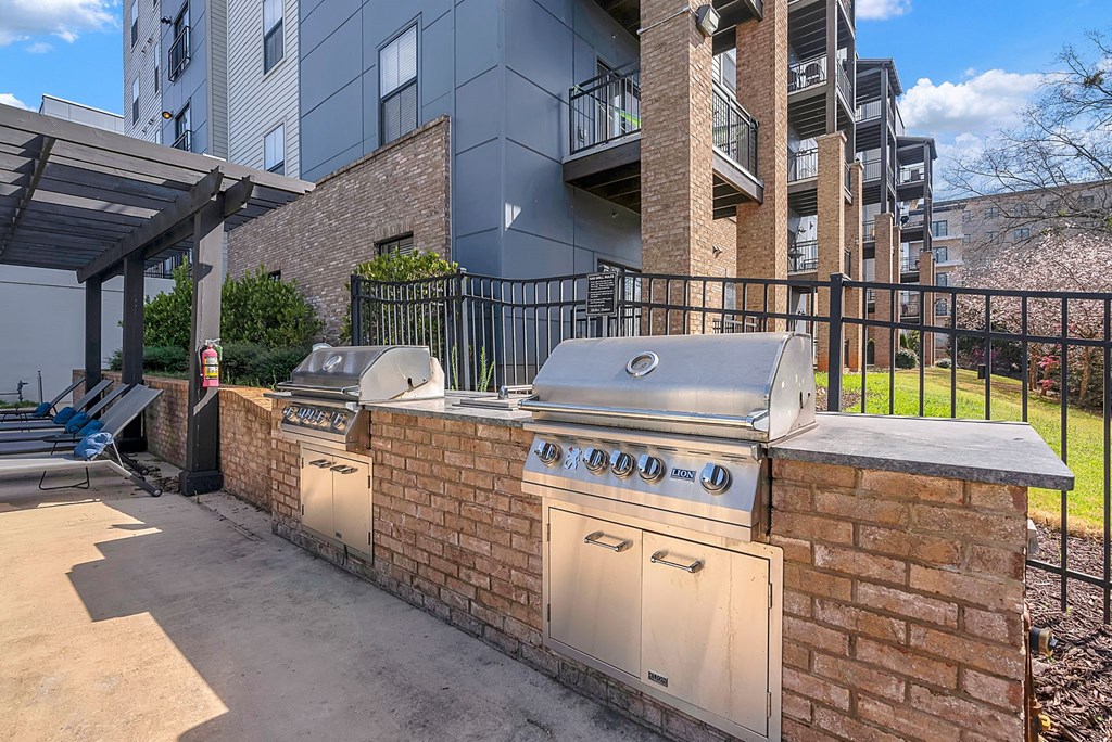 a brick outdoor grill area with a building in the background
