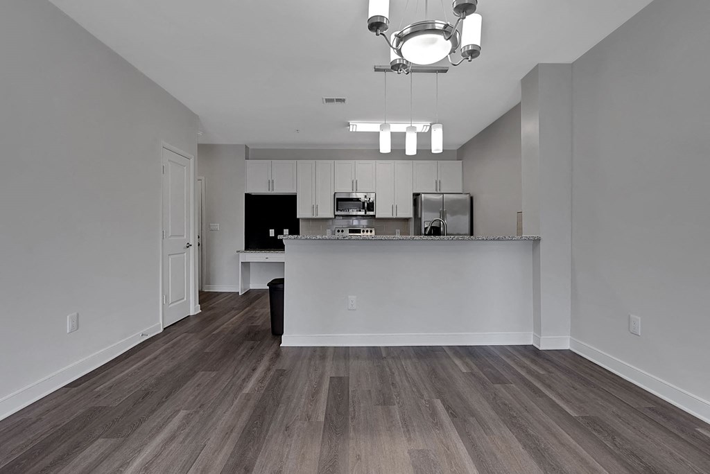 an empty living room with a kitchen and a counter top