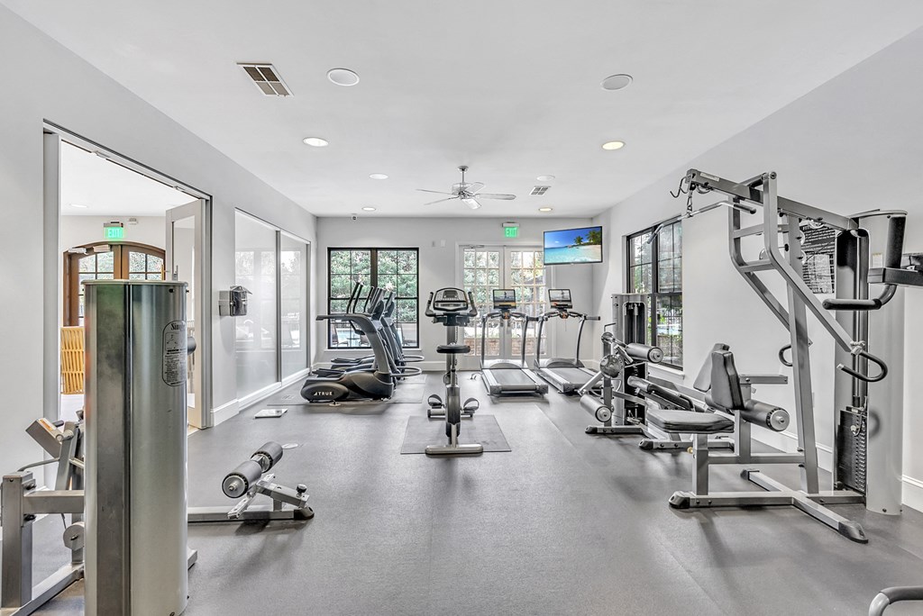 a gym with cardio equipment and glass doors