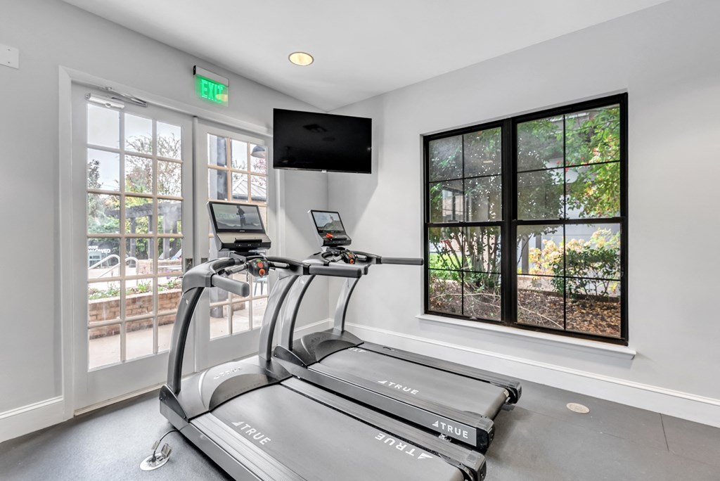the apartment cardio room has a treadmill and a tv