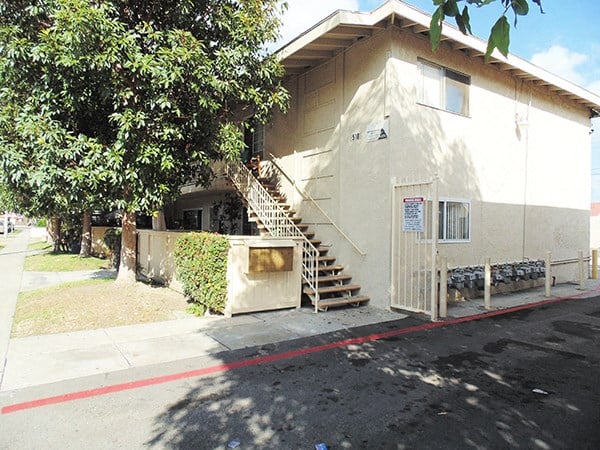 the front of a white building with stairs and a fence