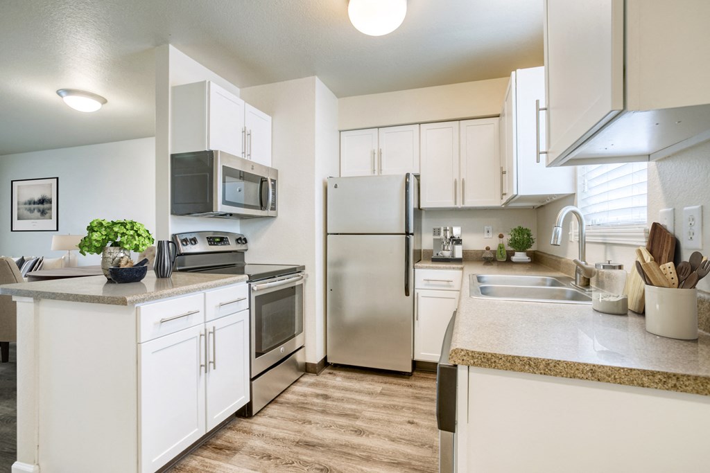 an open kitchen with white cabinets and stainless steel appliances