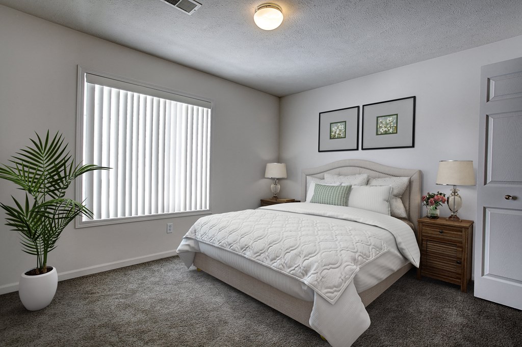 a bedroom with a white bed and a potted plant
