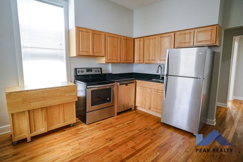 A kitchen with wooden cabinets and a stainless steel refrigerator.