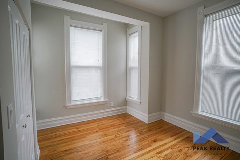 A room with wooden floors and two windows.