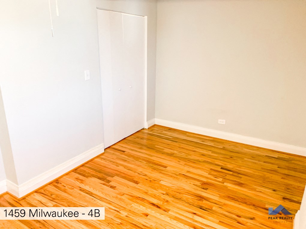 a room with wood flooring and white walls and a door