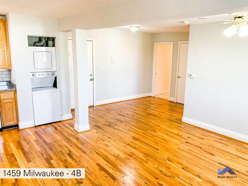 the living room and kitchen of a house with wood flooring and white walls