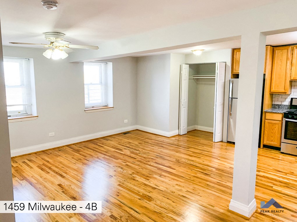 an empty living room with a hard wood floor and a ceiling fan