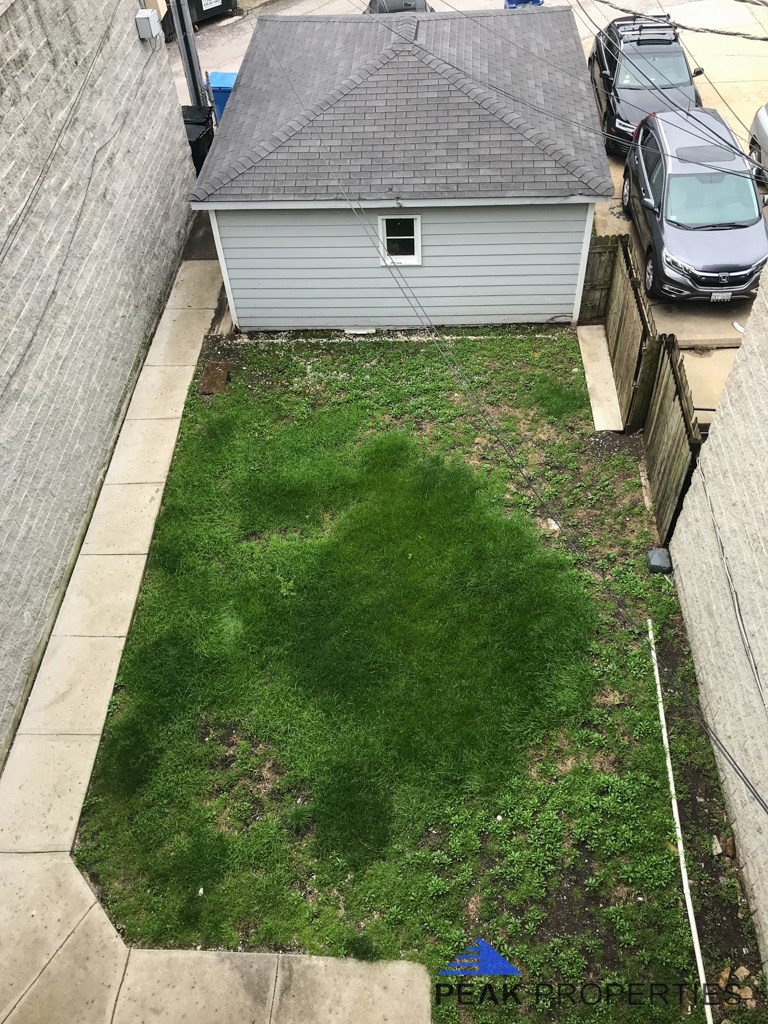 an aerial view of a yard with a house and cars in the driveway