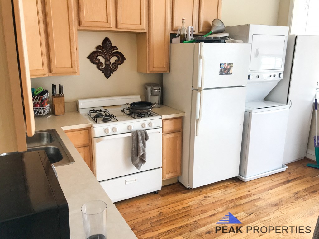 a small kitchen with white appliances and wooden floors