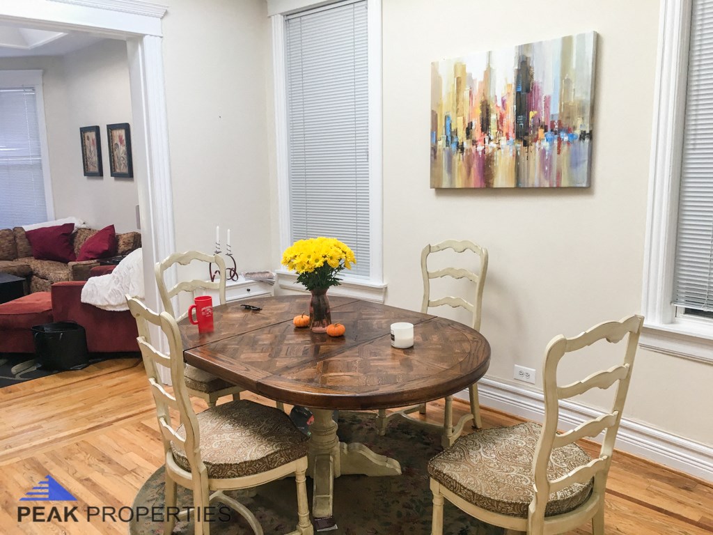 a dining room with a table and chairs and a painting on the wall