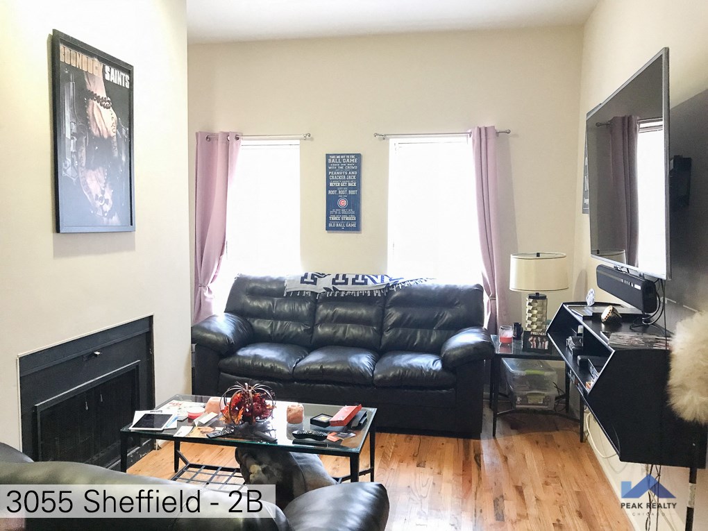 a living room with a black leather couch and a tv