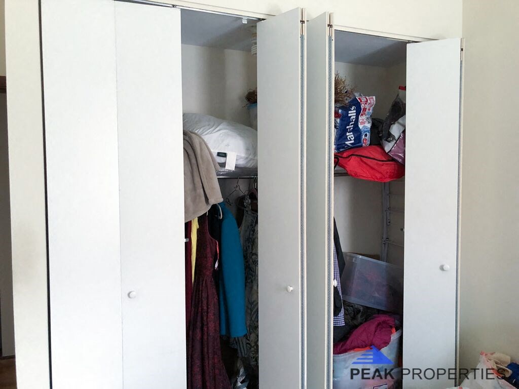 a closet filled with clothes and a bed in it