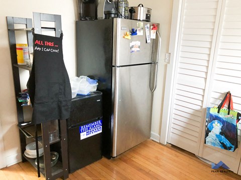 a refrigerator in the corner of a room with a wooden floor