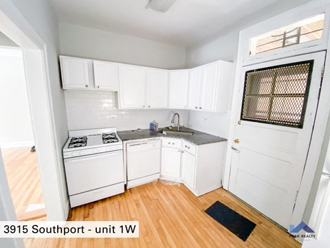 a kitchen with white cabinets and white appliances and wood floors