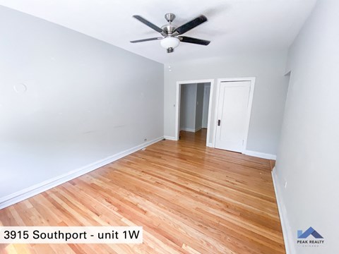 the interior of a room with wood flooring and a ceiling fan