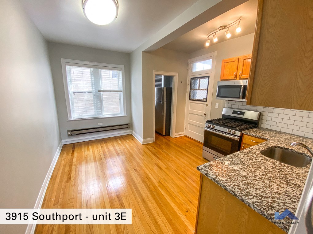 an empty kitchen with wood flooring and granite counter tops