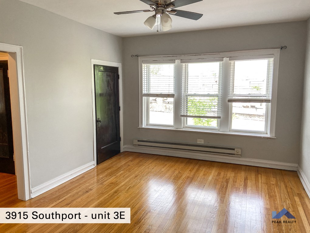 an empty living room with wood floors and a ceiling fan