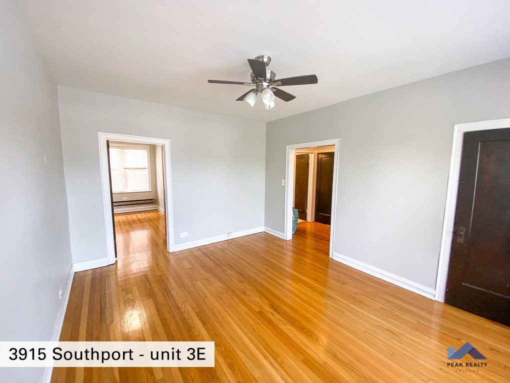 an empty living room with wood floors and a ceiling fan