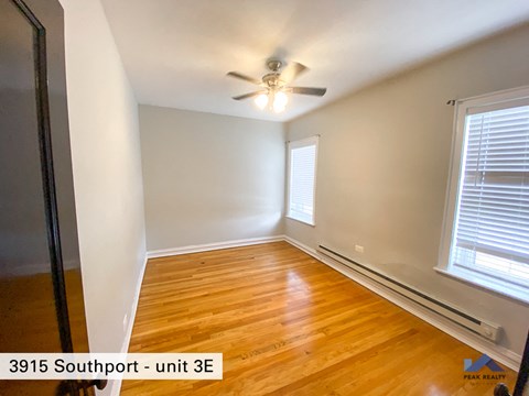 the bedroom of a home with wood flooring and a ceiling fan
