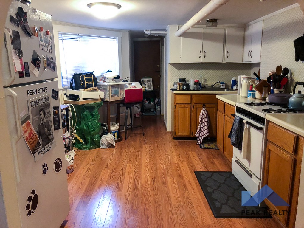 a cluttered kitchen with a stove and a refrigerator