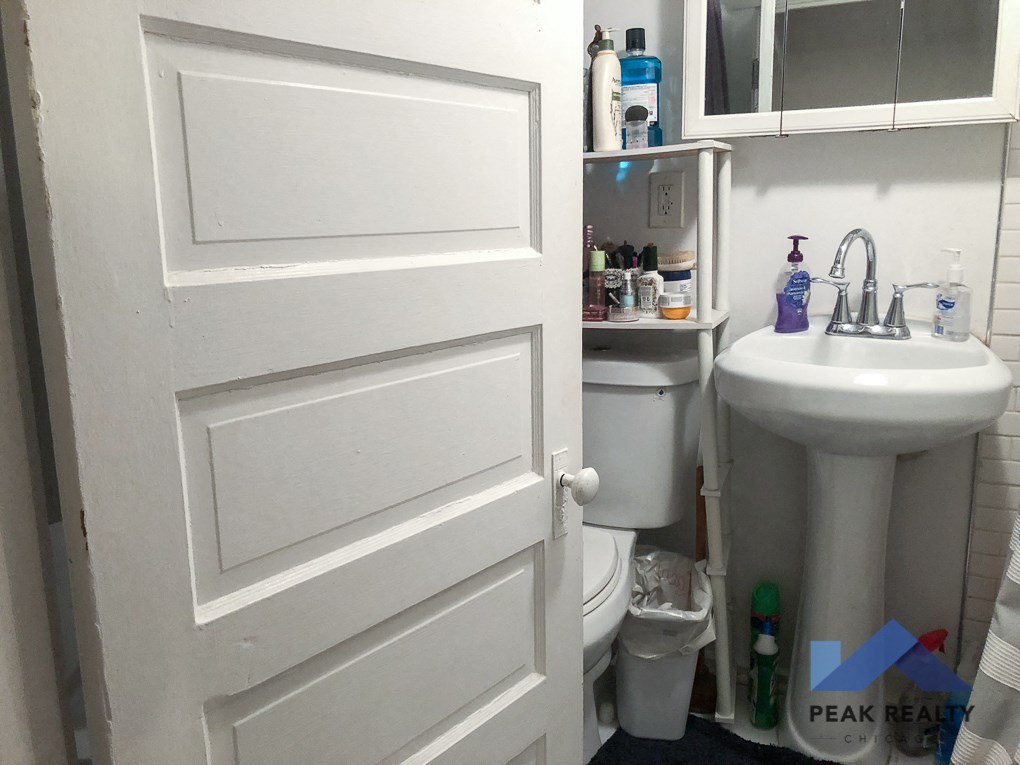 a bathroom with a white door and a sink and a toilet