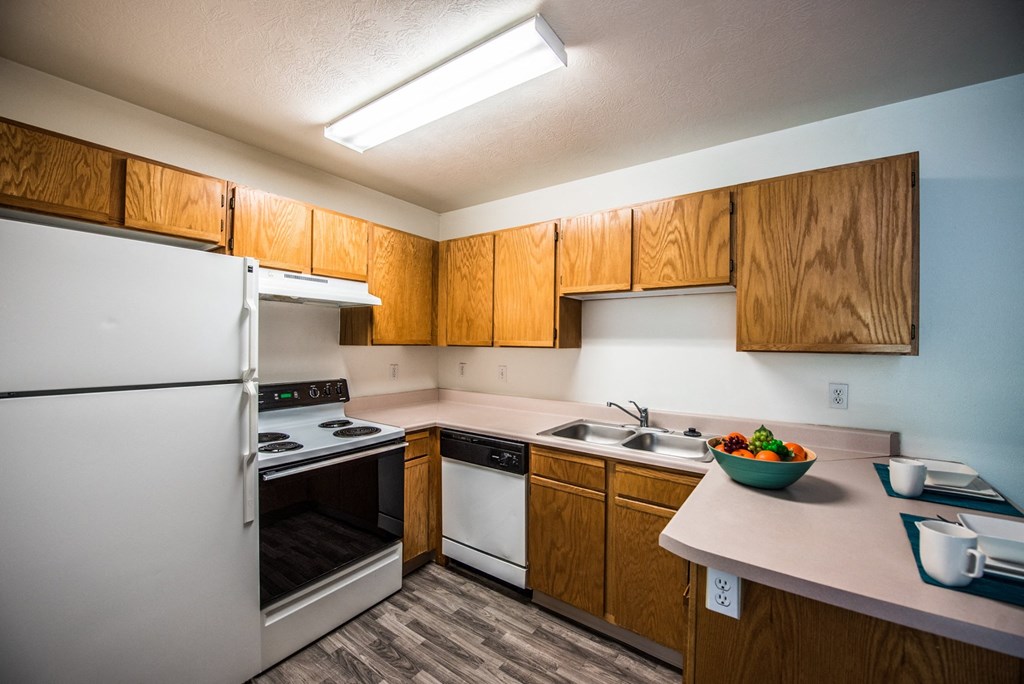 A kitchen with a white refrigerator and wooden cabinets.