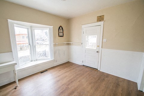 an empty living room with a door and two windows