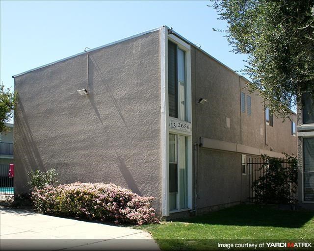 the side of a building with a sidewalk and bushes