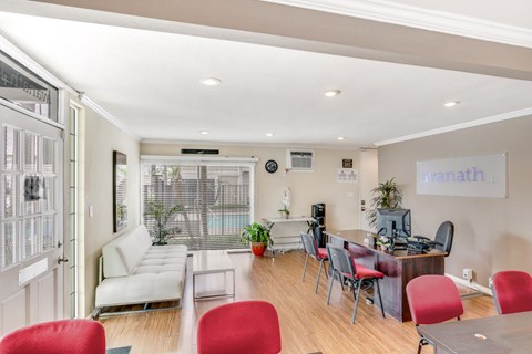 A living room with a white couch and red chairs.