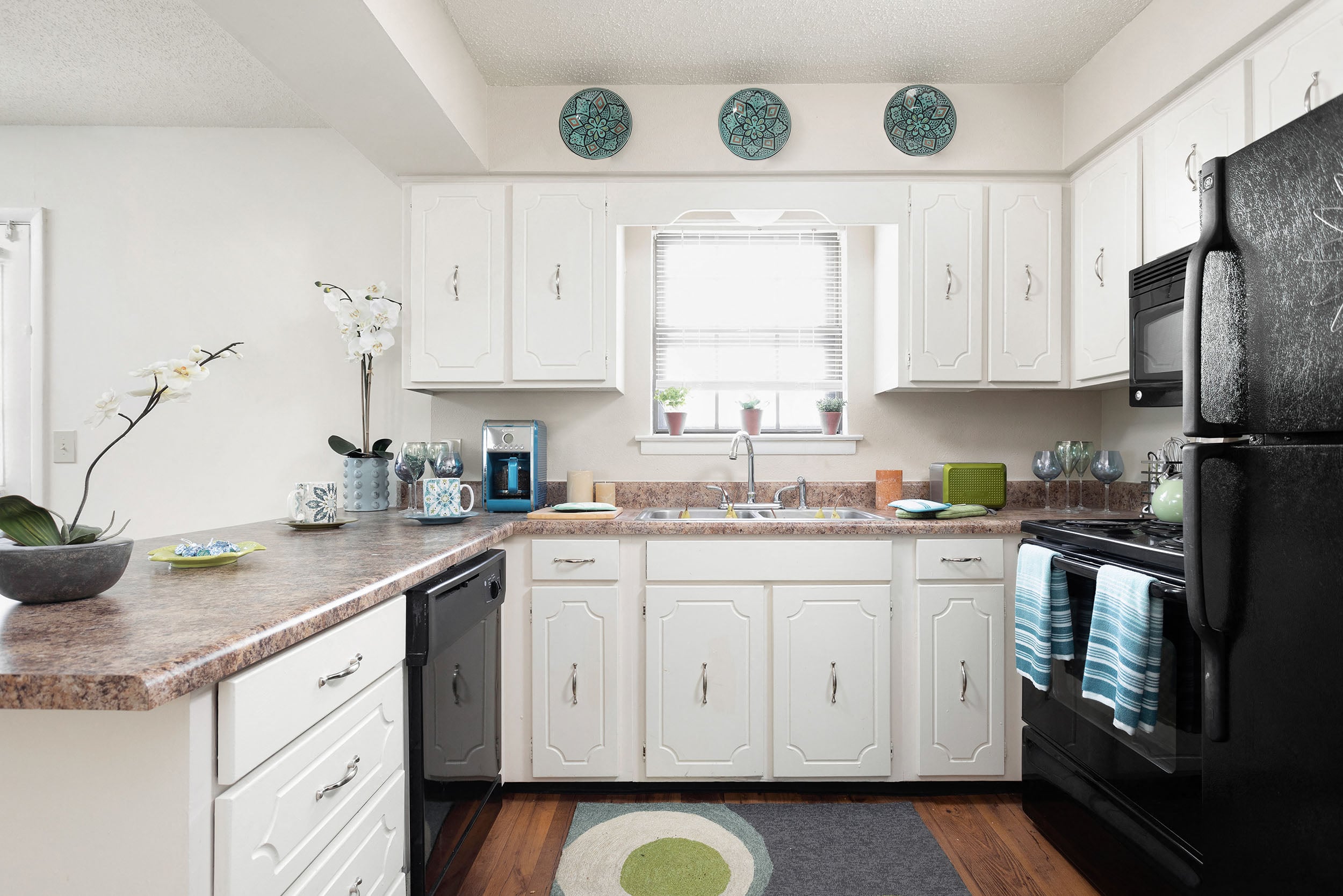 A kitchen with white cabinets and a black refrigerator.