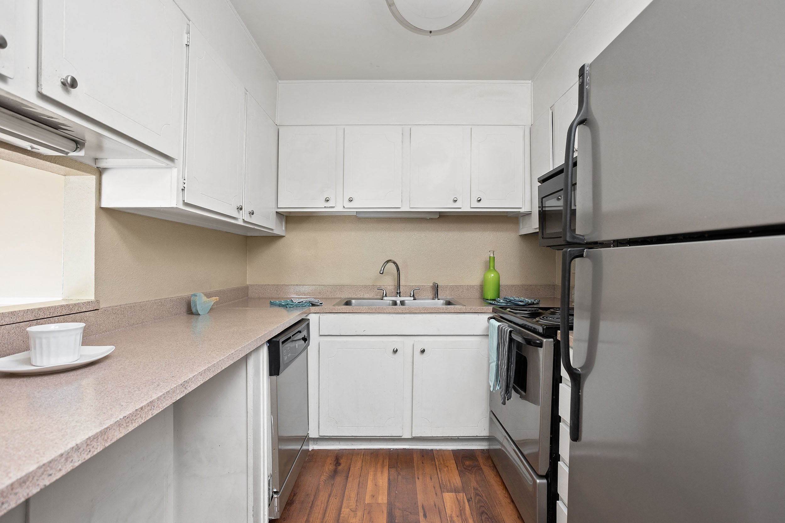A kitchen with white cabinets and a black refrigerator.