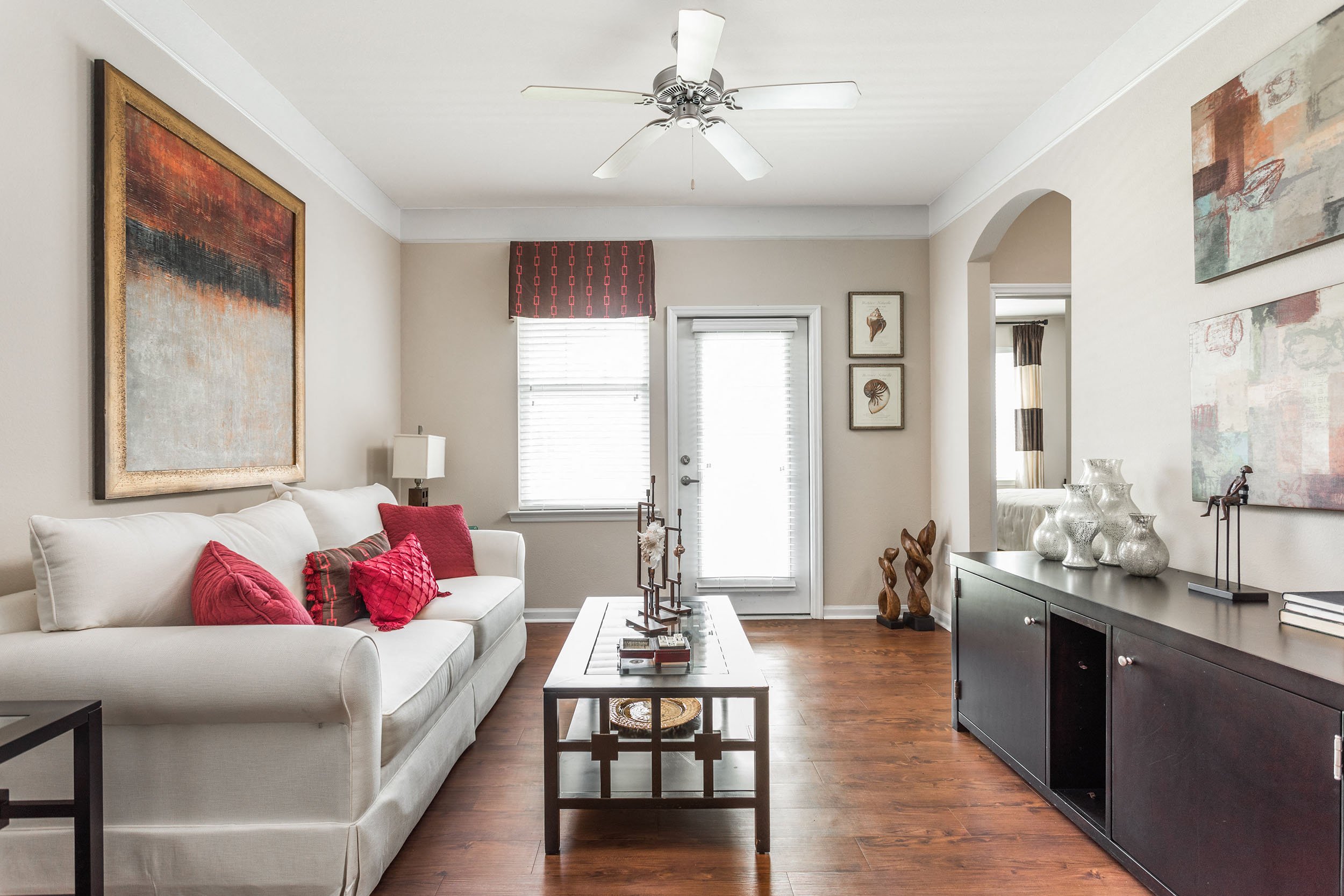 A living room with a white couch and a painting on the wall.