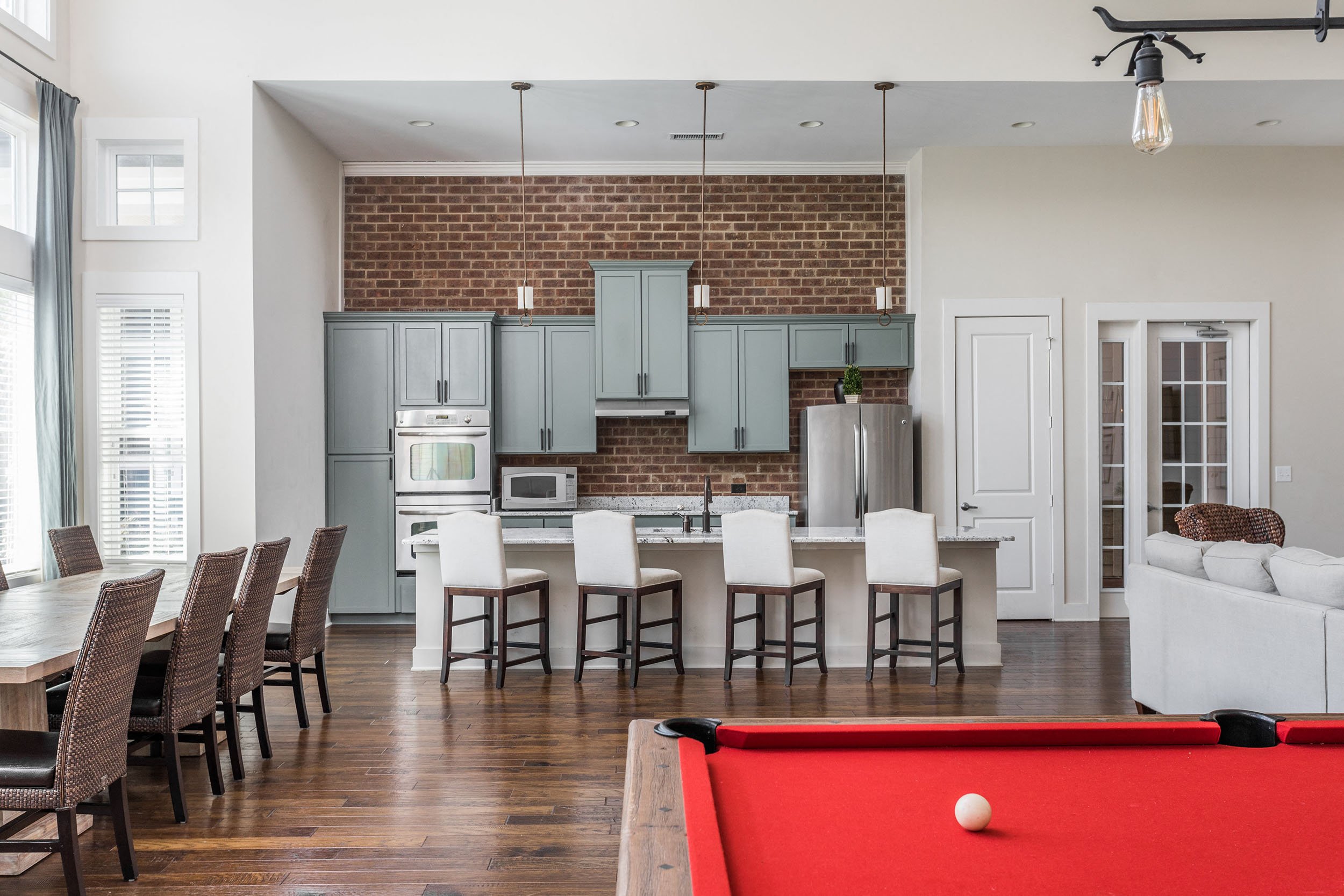 A pool table is in the middle of a kitchen and dining room.