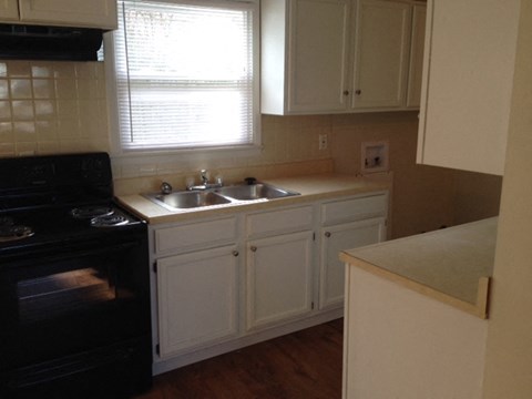 A kitchen with a black oven and white cabinets.