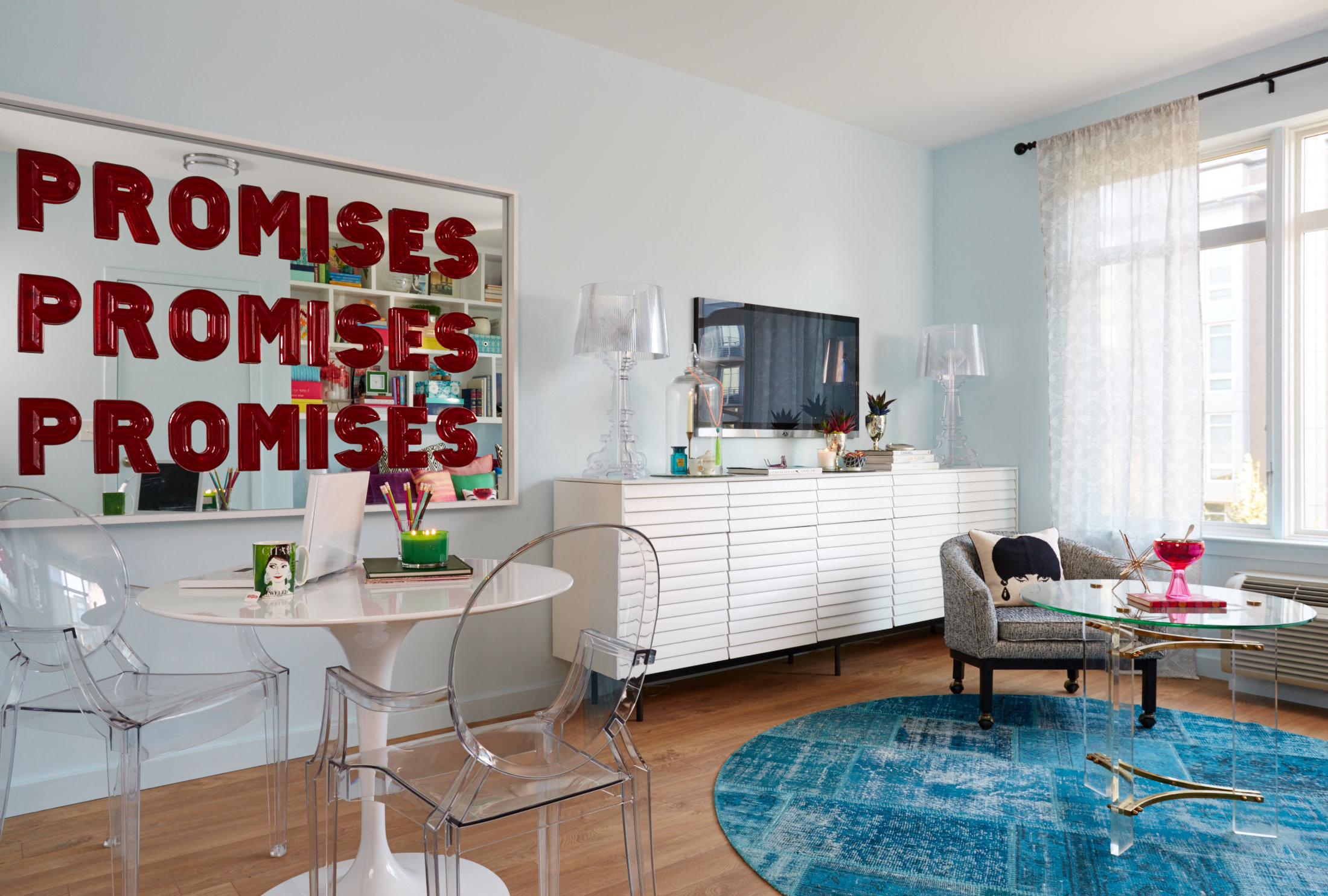 a living room with a table and chairs and a large poster on the wall