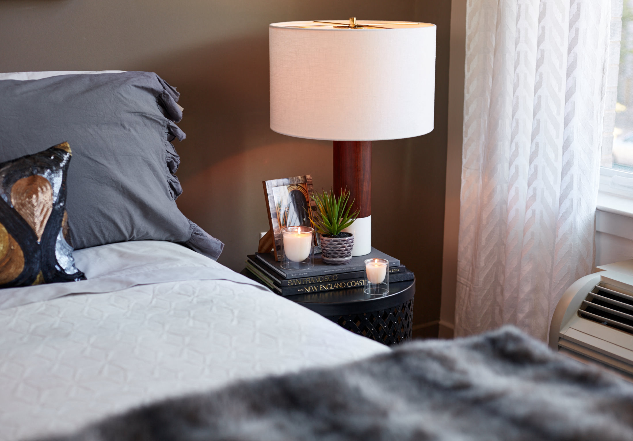 a bedroom with a bed and a lamp and a table with candles and a plant