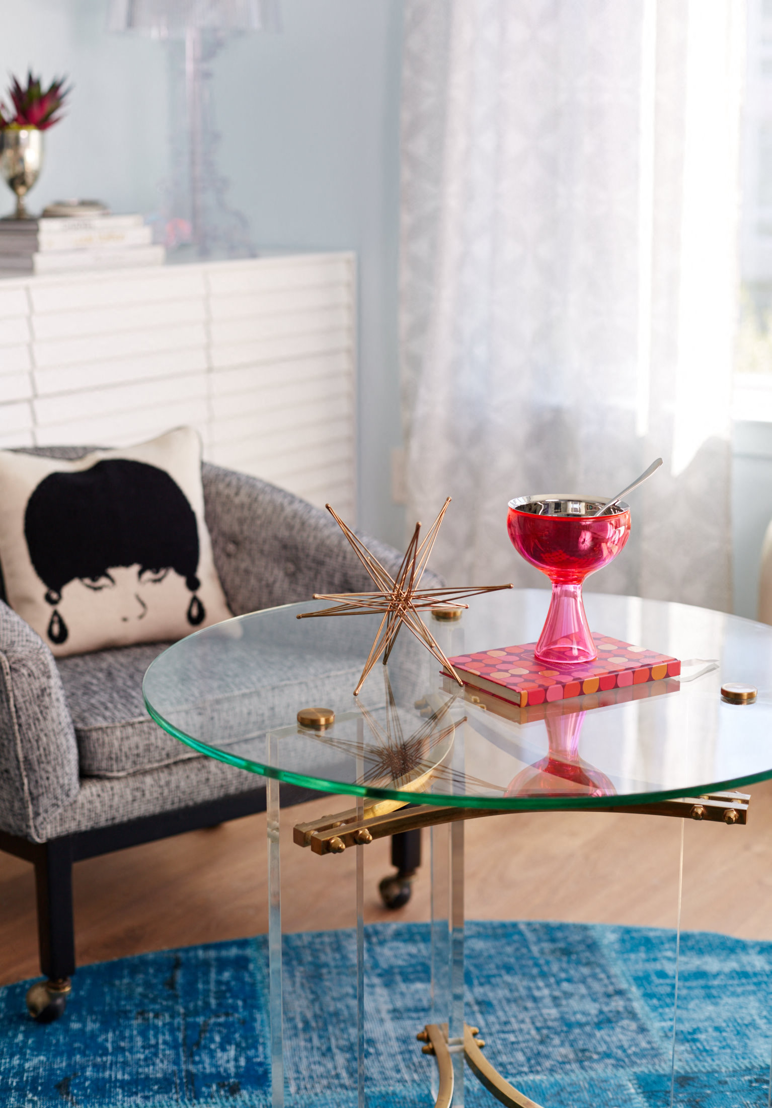 a living room with a glass coffee table and a chair