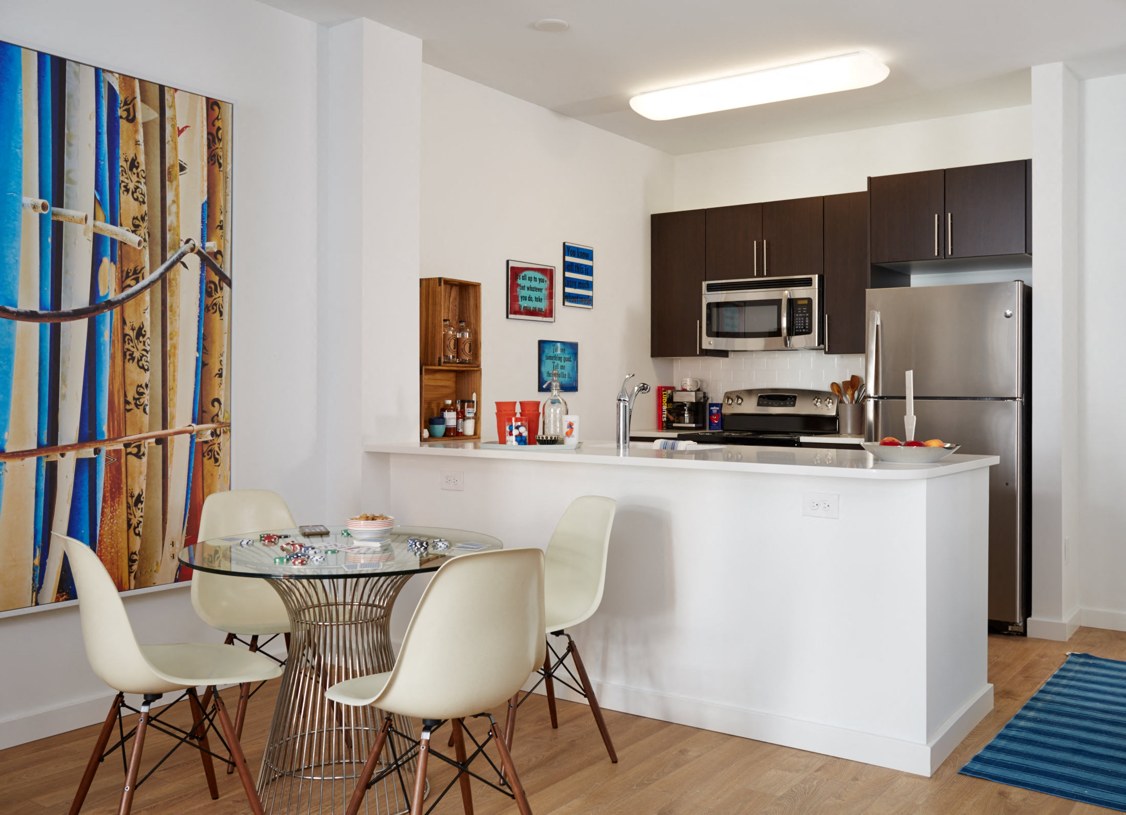 a kitchen and dining area with a small table and chairs and a refrigerator and microwave