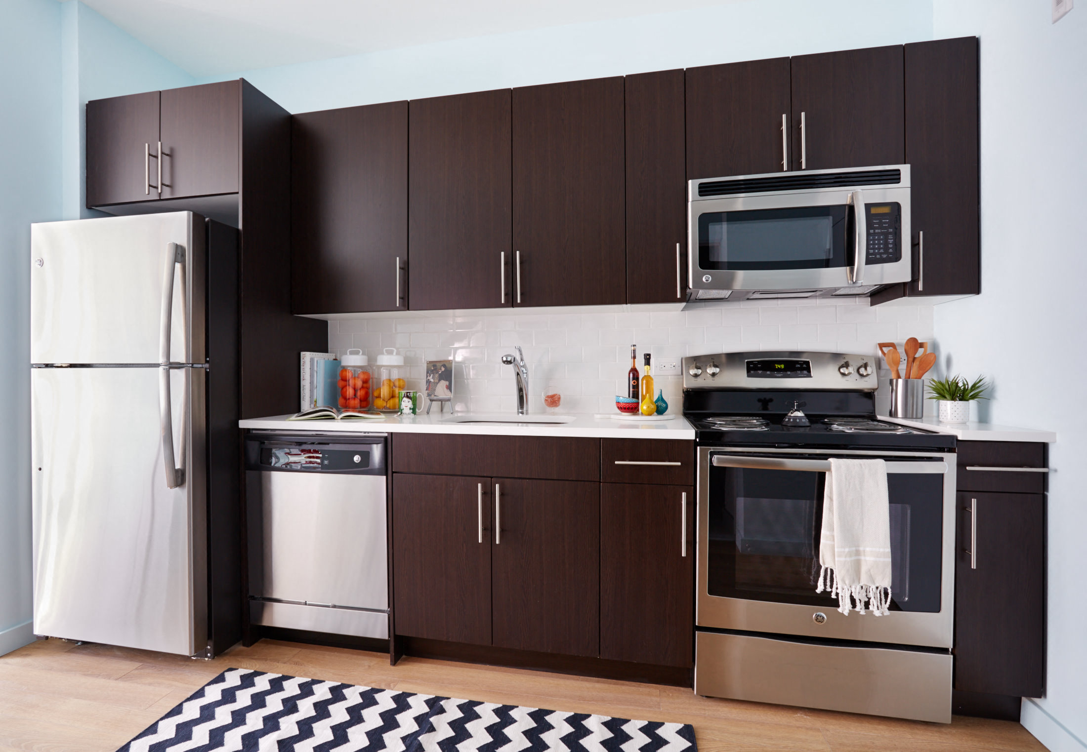a kitchen with stainless steel appliances and black and white rug